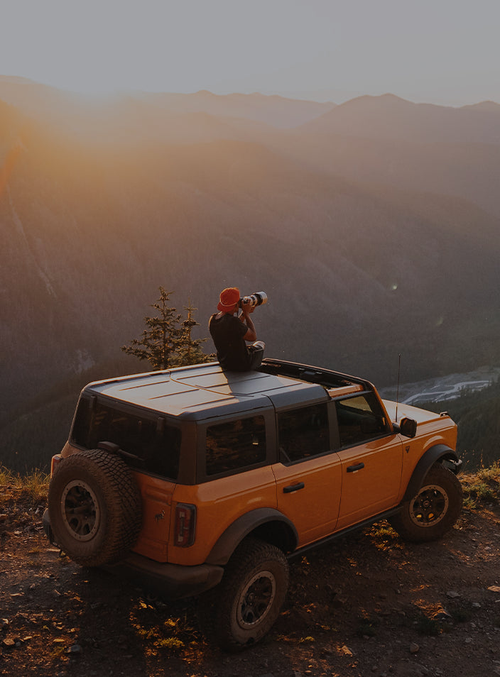 SeaBear Ambassador Mikey Holmquist sitting on a Ford Bronco atop a mountain overlooking a Pacific Northwest landscape | SeaBear Smokehouse